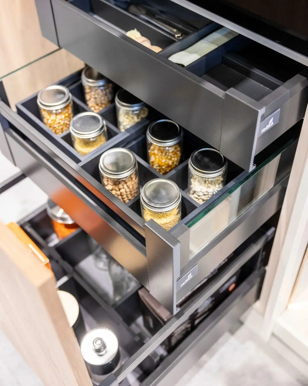 Hettich Vorratsschubladen mit Glaseinsätzen und Gewürzgläsern. Tiroirs Hettich avec inserts en verre et bocaux d’épices.